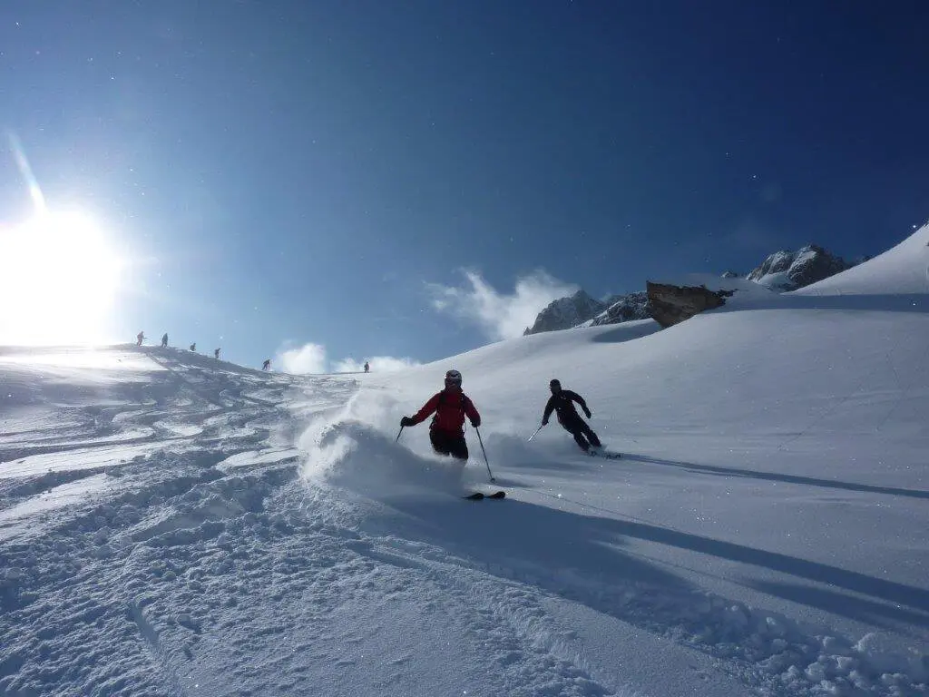 Zwei Teilnehmende der SkiAlpinfahrten der DAV Sektion Augsburg fahren im Tiefschnee die Piste herunter. | © Hartmut Seelus