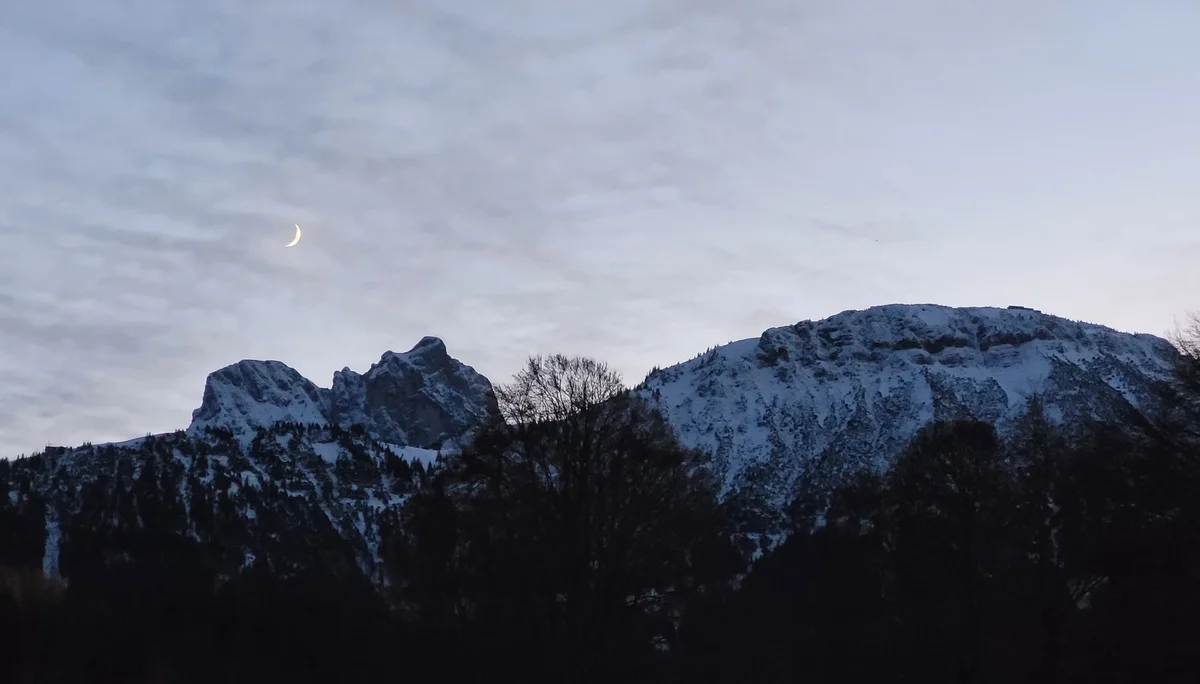Blick auf schneebedeckte Berge mit Mondsichel | © Aron Nuber