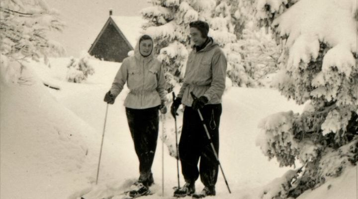 Das Titelbild der alpenblick Ausgabe 4-2022 der DAV Sektion Augsburg e.V. Ein Paar steht im Schnee vor der Quenger Alm. Das Bild stammt von 1952. | © Wolfgang Weber