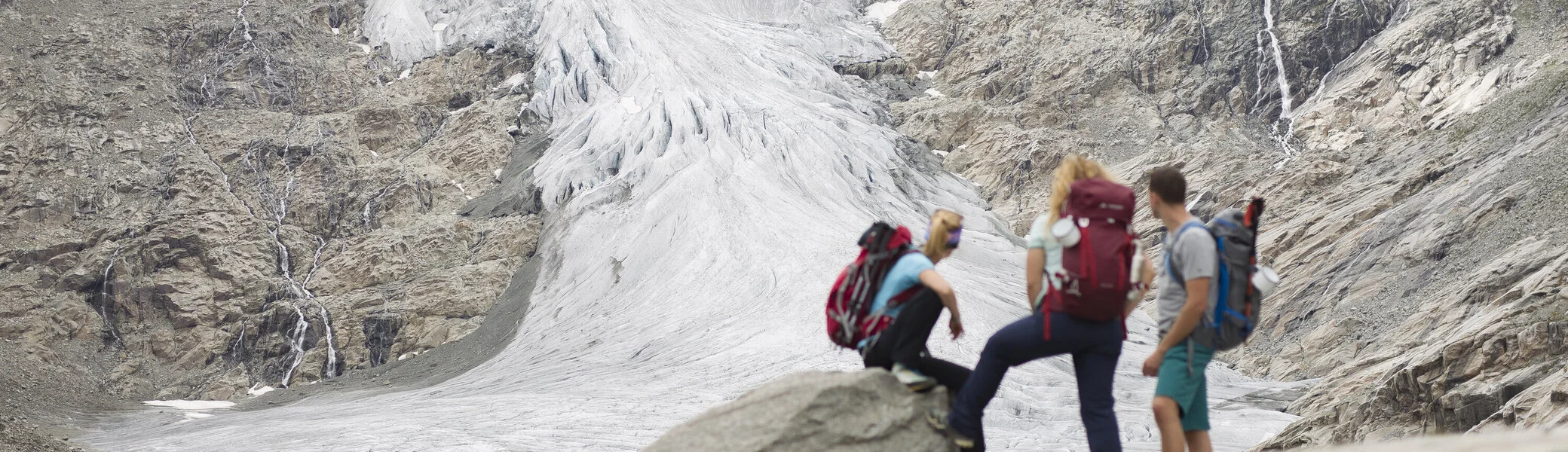 Drei Wandernde blicken nahe der Neuen Prager Hütte am Großvenediger auf den verschwindenden Gletscher. | © DAV / Jens Klatt