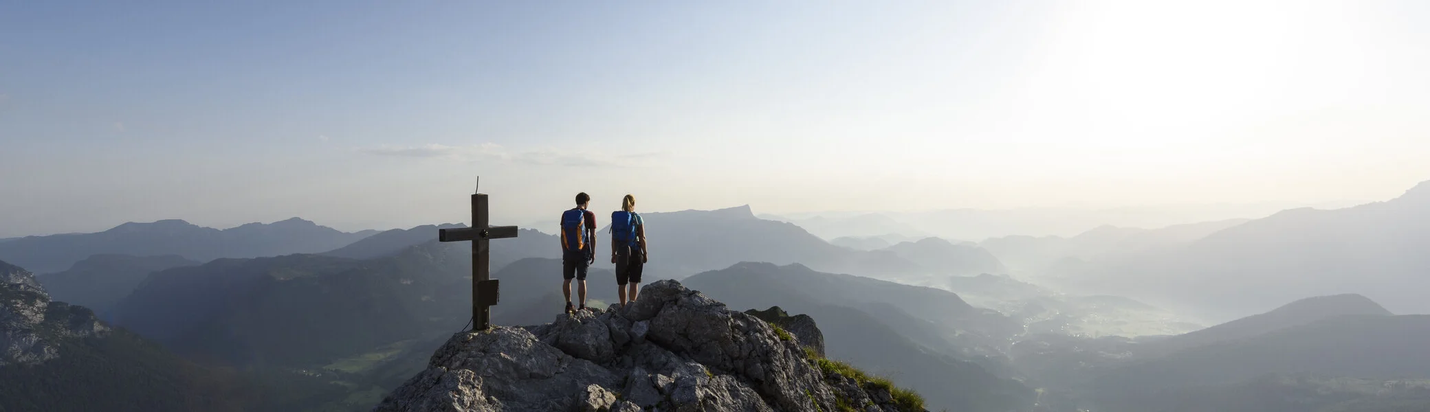 Zwei Wanderer auf einem Berggipfel mit Gipfelkreuz - aus der Ferne fotografiert | © DAV/Wolfgang Ehn